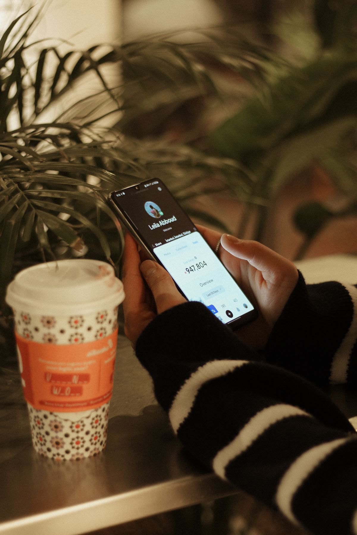 Hands using a smartphone beside a coffee cup